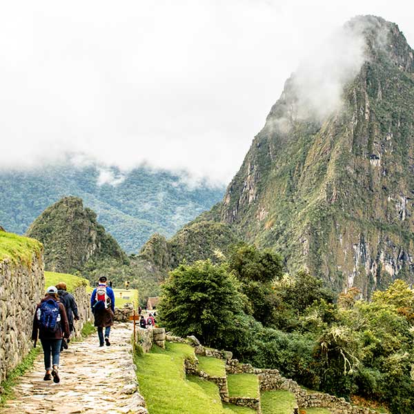 Hiker arriving at Machu Picchu via the Short Inca Trail with panoramic view of ancient ruins.